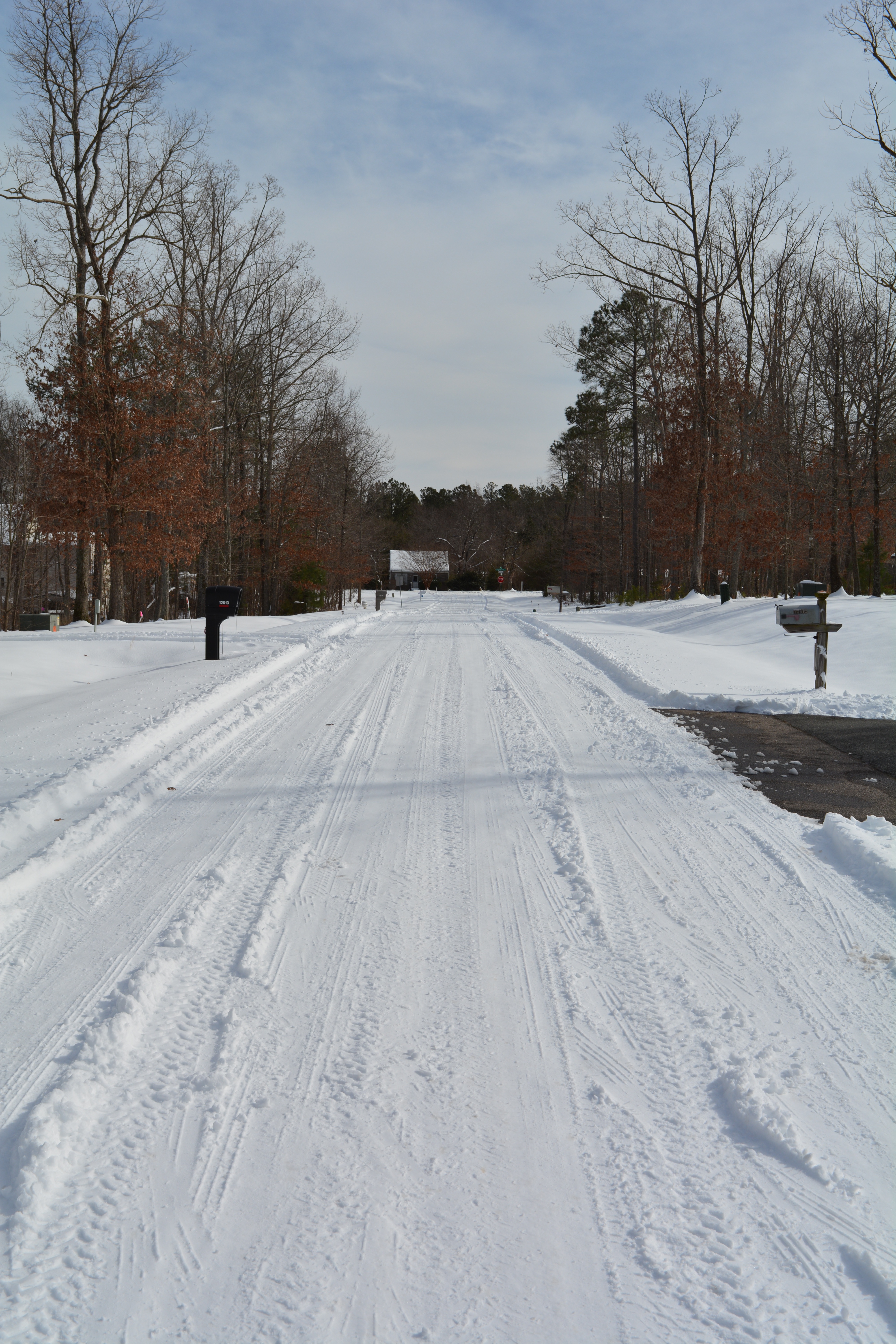 A small straight section of road in a snow covered subdivision.